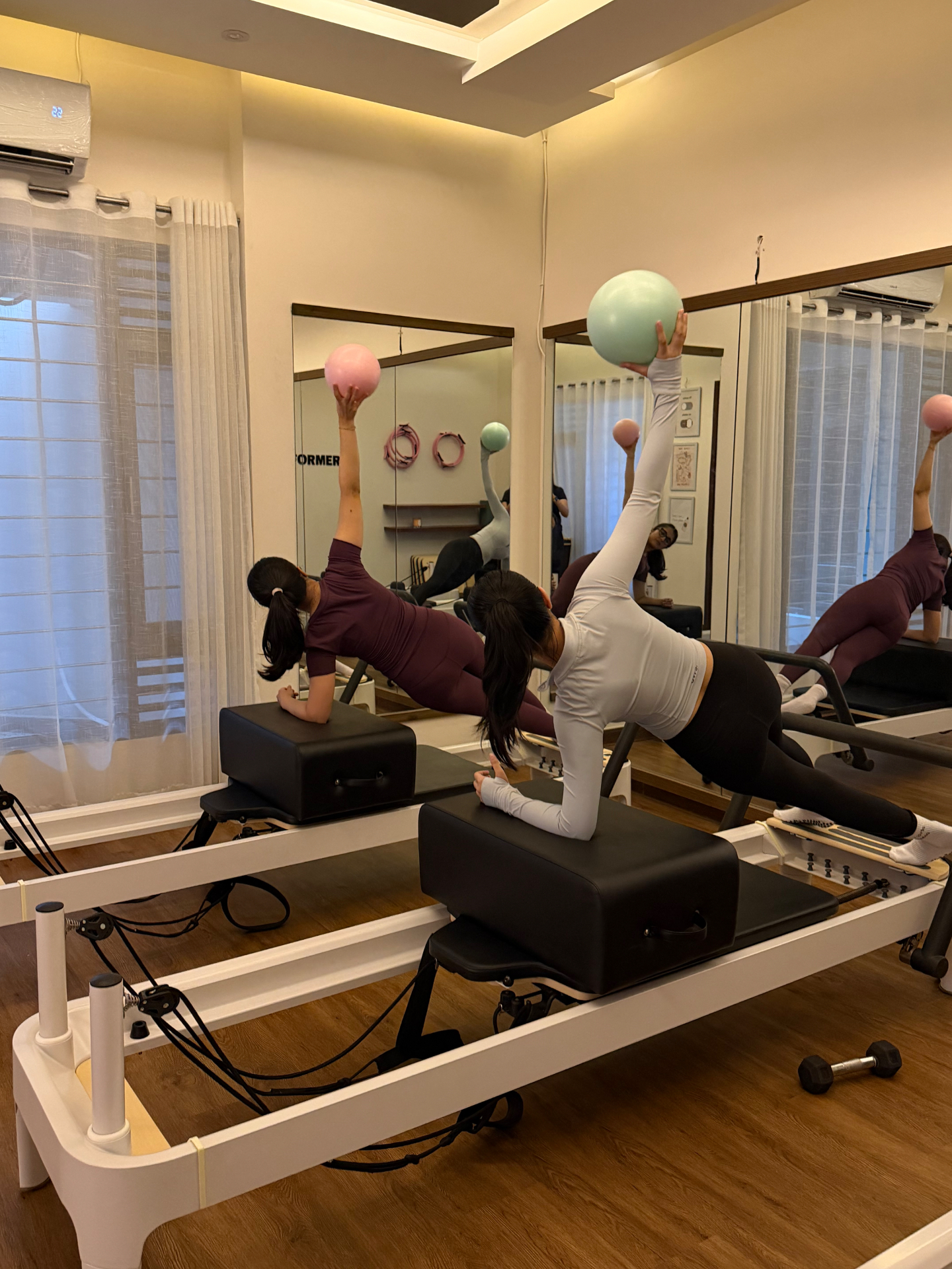 Clients working with Pilates balls on reformers